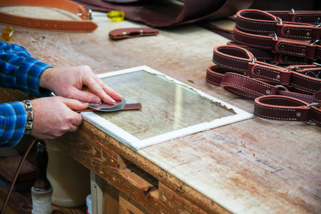 Man cutting leather so it will lay flat when stitched together to form a horse hobble
