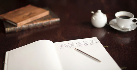 Writing a book with pen on paper pad, coffe and sugar bowl in the distance. Reference books close at hand.の写真素材