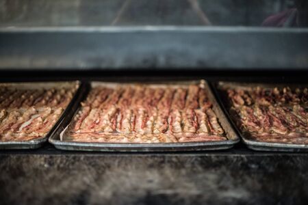 Three Trays of Bacon cooking at restaurantの写真素材
