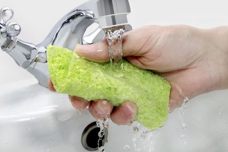 hand with green cloth under running waterの写真素材