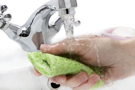hand  with a green cloth under running waterの写真素材