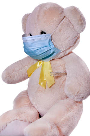 toy bear with a yellow bow in a protective medical mask isolated on a white backgroundの写真素材