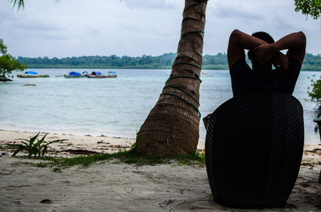 Man Sitting on a Chair relaxing at the beachの写真素材