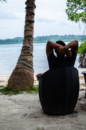 Man Sitting on a Chair relaxing at the beachの写真素材