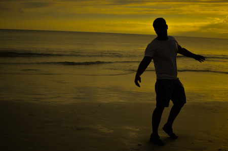 Man doing Open Arms Gesture under Setting Sunの写真素材