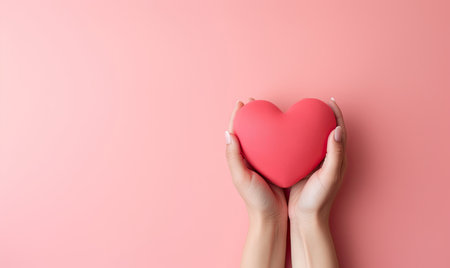 Female hands delicately holding a red heart on pastel background. Donor concept. Created with generative AI toolsの素材