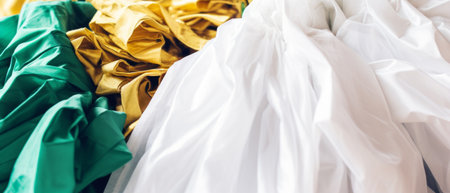 Elegant folds of green, white, and gold satin fabric, capturing the soft sheen of the material.の素材