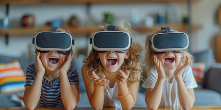 Three young girls are seated at a table, wearing virtual reality glasses. They appear engaged and enthusiastic, laughing and interacting with the digital world projected in front of them.の素材