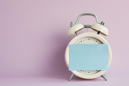 Minimalist Alarm Clock with Blank Blue Note on Purple Background.の素材