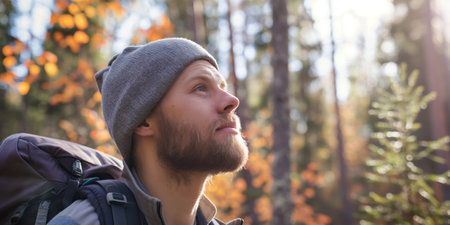 Man with Backpack in Autumn Forest Admiring Nature on a Hike.の素材