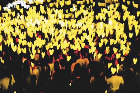 Crowd of People with Glowing Yellow Heart Lights in a Night Event.の素材