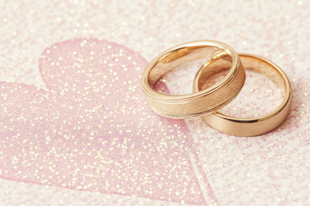 Golden Wedding Rings on Sparkling Pink Heart Symbol of Love and Commitment.の素材