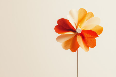 Vibrant Orange and Yellow Paper Flower on Minimalist Beige Background.の素材