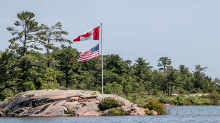 Canadian and American flags on a flag pole in Killarney, Ontario, Canadaのeditorial素材