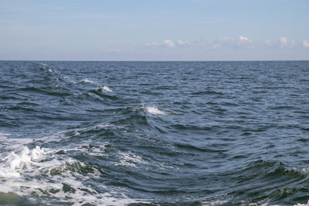Sea waves on the surface of the water. Blue sky with white clouds.の写真素材