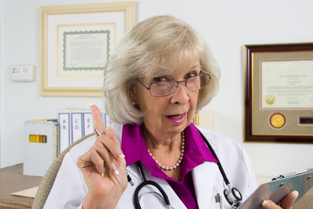 A woman doctor sitting at her desk appears to be giving a warning on a medical subject の写真素材