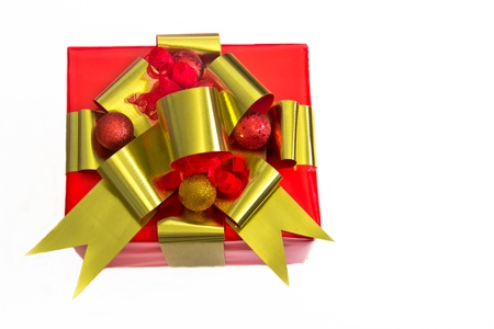 A red-wrapped gift is topped by gold ribbons, red and gold balls and red curly ribbons.の写真素材