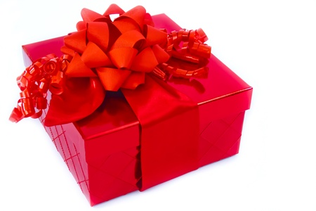 A present in a red gift box is trimmed with a big red bow and red curly ribbons.の写真素材