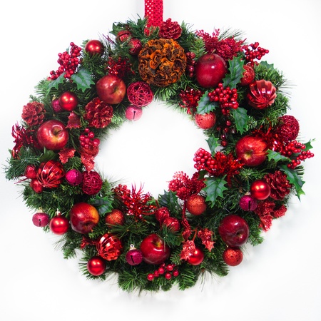 A green wreath is decorated with red apples, bells, berries, balls and pine cones.の写真素材