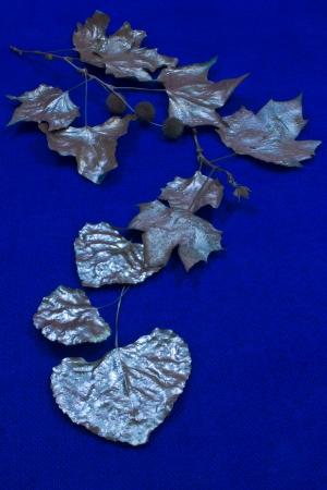 Silver leaves are patterned against a blue woven background の写真素材