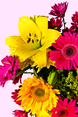 A yellow lily is featured in a mixed bouquet with magenta asters and a yellow sunflower.の写真素材