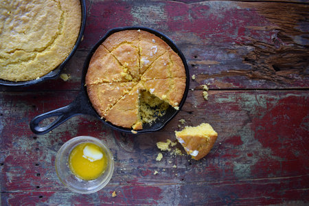 Yellow Cornbread in cast iron skillet on rustic wood table top viewの写真素材