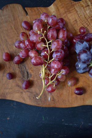 red and blue grapes on wooden cutting board top viewの写真素材