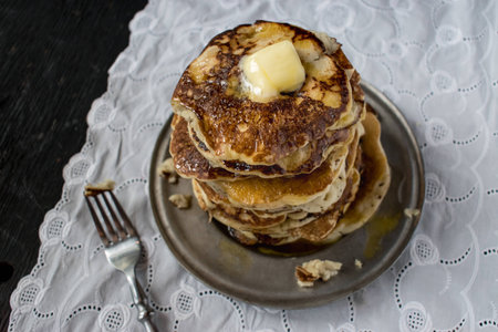 tall stack of hotcakes with butter and syrup on white linenの写真素材