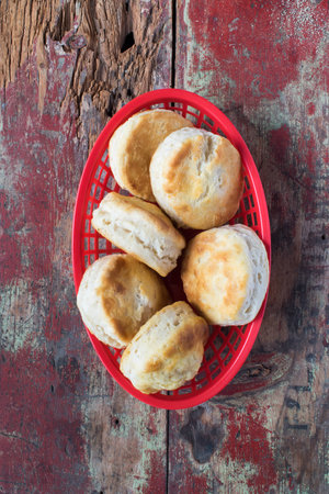 Country biscuits in red basket on rustic painted table in top down viewの写真素材