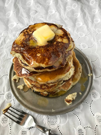 tall stack of hotcakes with butter and syrup on white linenの写真素材