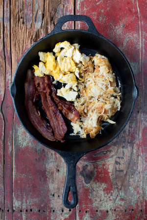 Scrambled eggs, bacon, and hashbrowns in cast iron panの写真素材