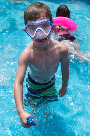 smiling young boy in swim goggles at poolの写真素材
