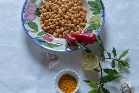 chickpeas in a bowl with turmeric, red chillis, lemon and garlic, on a white table cloth,の写真素材