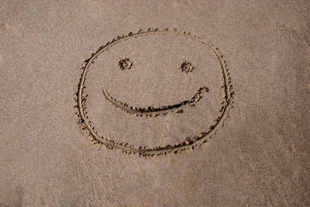 Smiling face drawn in the sand on the beach. High quality photoの写真素材