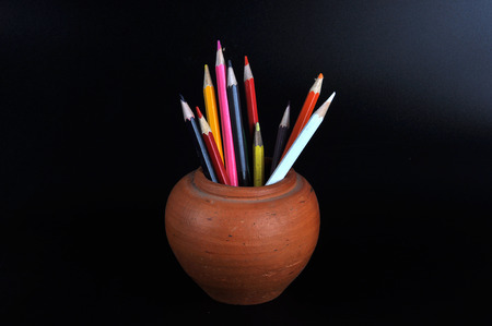 colored pencils in a clay jug  on black backgroundの写真素材