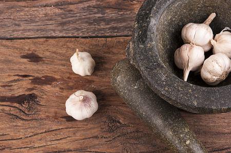 Stone mortar and pestle with garlic old wood boardの写真素材