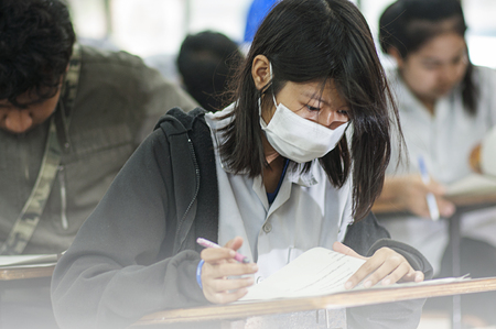 female college student sitting an exam in a classroomの写真素材