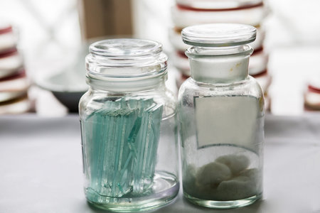 Bottles with glass pieces and swabs in a lab; Petri dishes stacked on the background