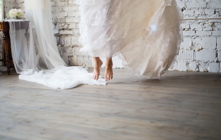 Bride jumping barefoot in rustic white wedding dress. Beautiful wedding gown. Loft style wedding.の写真素材
