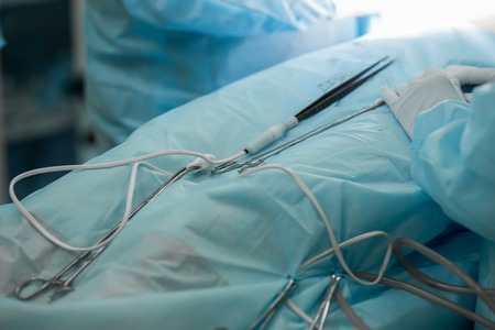 Close-up image of surgical instruments during cosmetic surgery on breasts. Forceps and tweezers, doctor operating a patient. Plastic surgery, breast augmentation, enlargement, enhancement. Hands of a surgical team during surgery.の写真素材