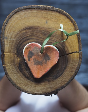 Valentines day. Woman holding handmade painted heart shape on wood slice. Valentine's Day love concept. Happy romantic feeling.の写真素材