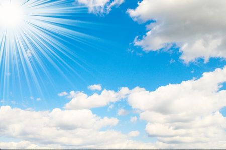 Blue sky is covered by white clouds and sun beams.の写真素材