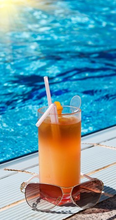Sunglasses and tasty cocktail with lemon next to swimming pool.の写真素材