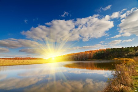 Beautiful lake, autumnal  wood and the blue sky  with clouds.の写真素材