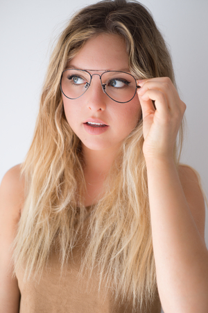 Pretty blonde hipster girl in glasses on white background and have funの写真素材