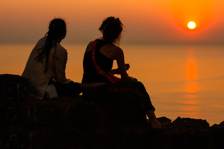 Two girls watching sunset on the seaの写真素材