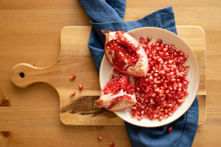 Pomegranate fruit lies on a plate on the table, top view.の写真素材