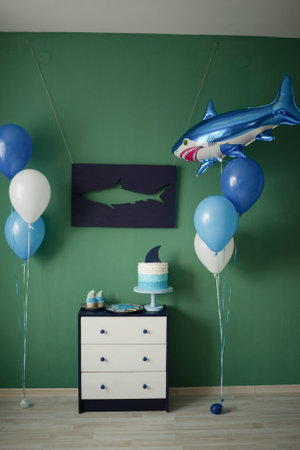 Home decoration of a children's holiday in the style of a shark, balloons and sweet pastries for childrenの写真素材