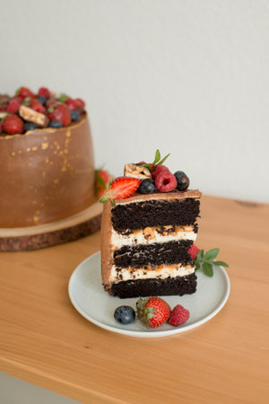 A piece of cake decorated with berries on a plateの写真素材