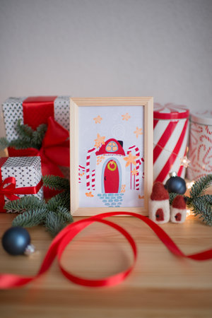A framed Christmas card stands on a table with giftsの写真素材